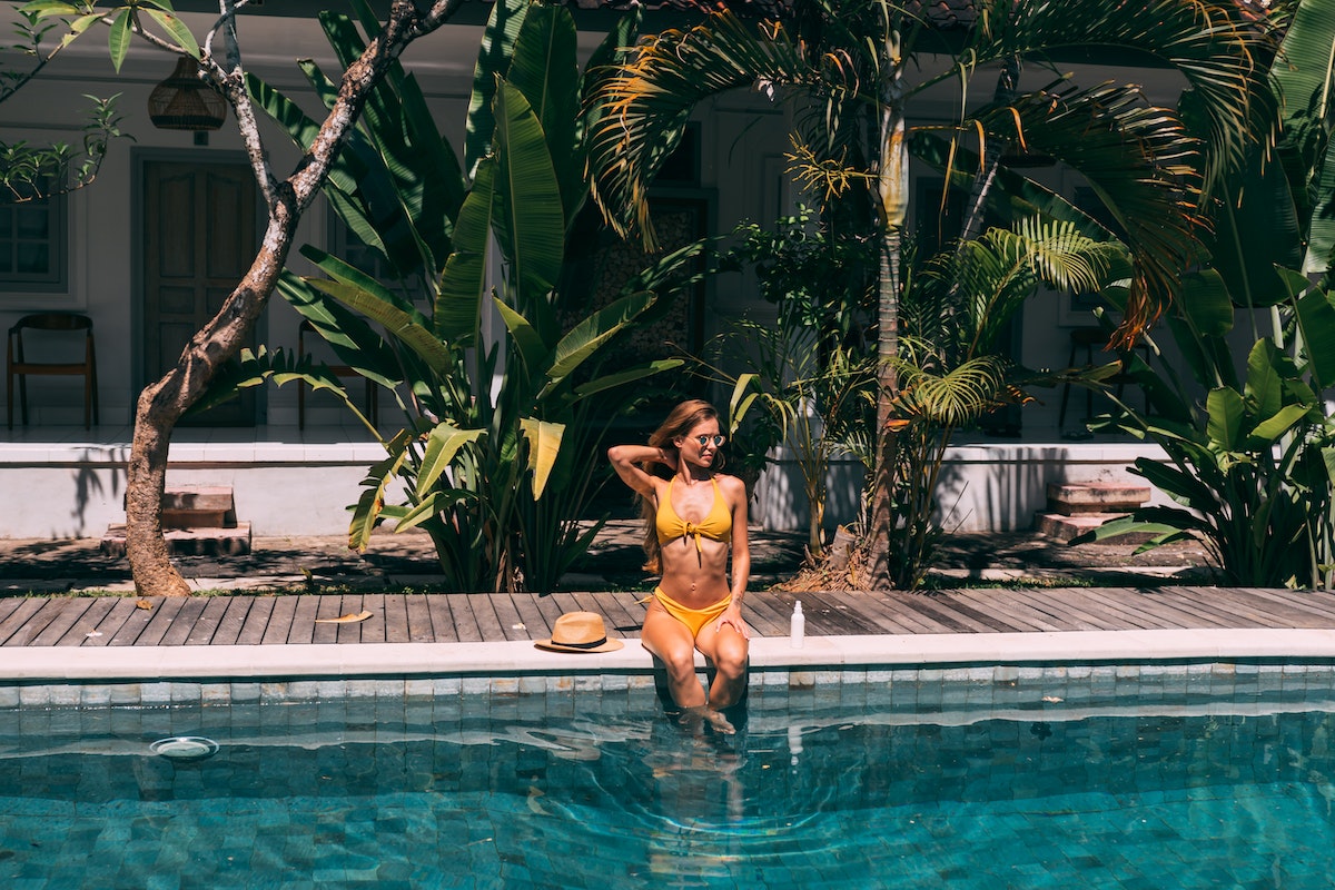 A Woman in Bikini Wear Sitting on the Side of the Pool