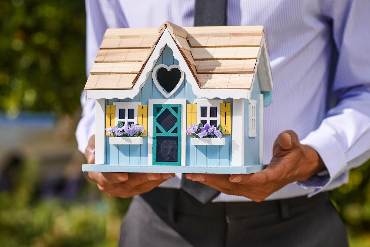 Person Holding a Miniature Wooden House